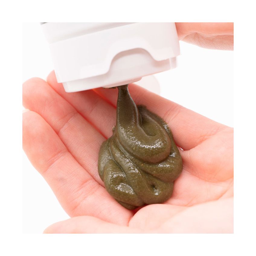 Guam being squeezed from a white container onto a hand against a white background