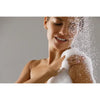 Woman washing her face with a sponge and water droplets around her.