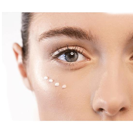 Close-up of a person's eye with a light-colored cream applied to the skin.