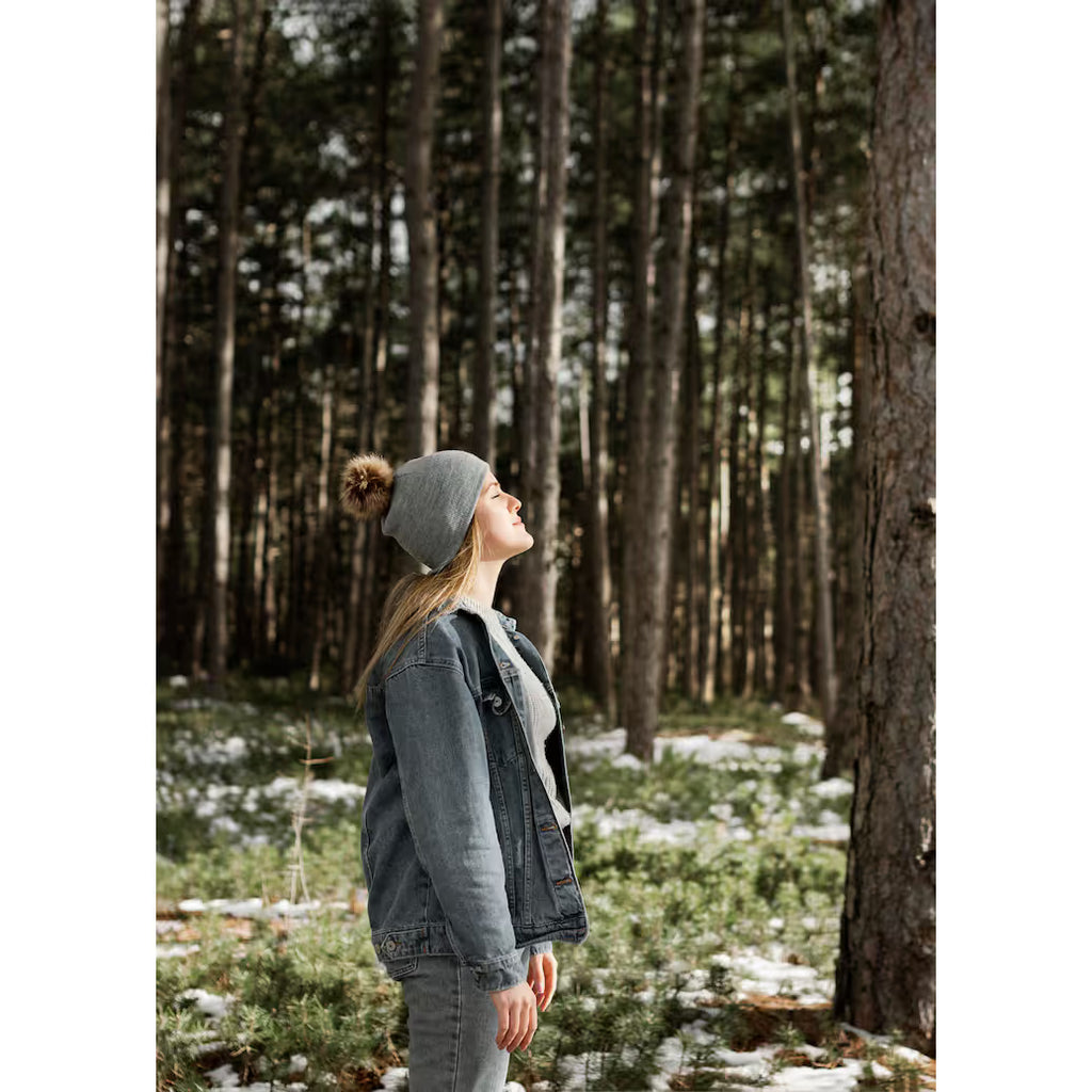 Person standing in a forest with trees and snow on the ground